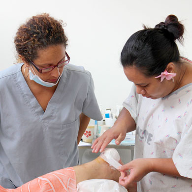 Two women in scrubs treat a foot wound.