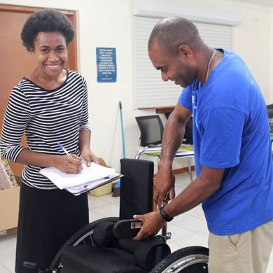 A male participant of the training adjusts a wheelchair, while a female participant checks off a list of changes that need to be made.