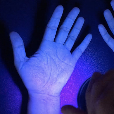 A hand under UV light shown to be clean.