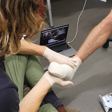 Tom demonstrates making a foot cast while on a video call with training participants.