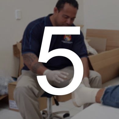 A man reaches out to dress a client's foot. The number 5 is displayed over the photo.