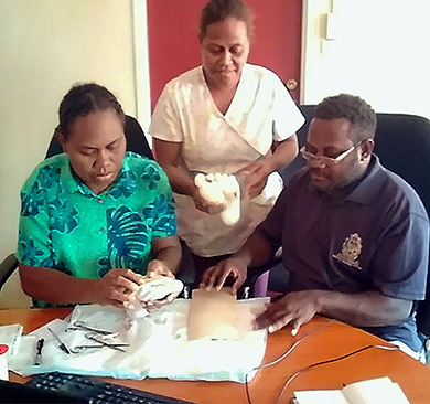 Three participants prepare materials for a foot wound treatment practice session.