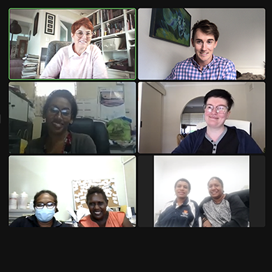 A group of eight people on a video call smile and talk.